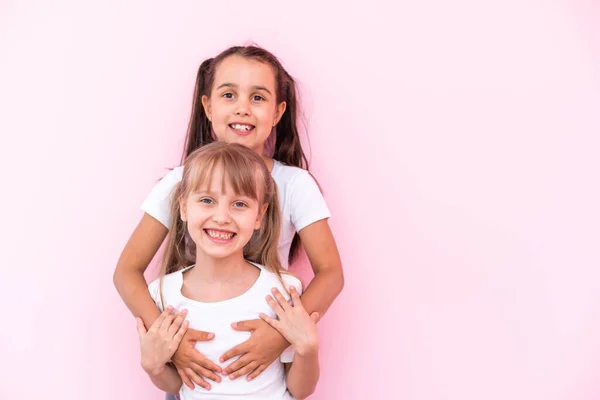 Två små flickor - bästa vänner, isolerade över på en rosa bakgrund — Stockfoto