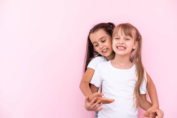两个小女孩- -最好的朋友，在粉红的背景下孤身一人 — 图库照片