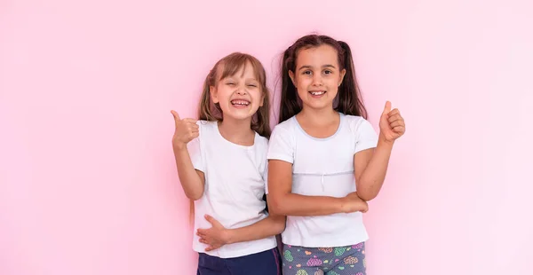 두 어린 소녀 - 가장 친한 친구들 - 는 분홍빛 배경 위에 따로 떨어져 있다 — 스톡 사진