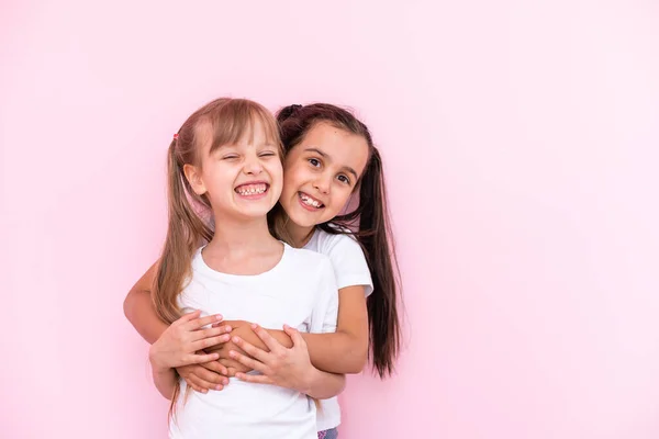 Twee kleine meisjes - beste vrienden, geïsoleerd over op een roze achtergrond — Stockfoto
