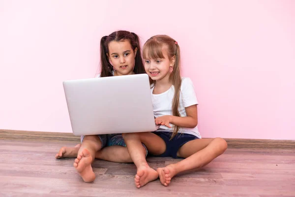 Zwei Mädchen arbeiten am Laptop, lächeln und ältere Schwester hilft jüngeren — Stockfoto