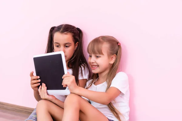 Meninas brincando em um tablet dispositivo de computação no chão — Fotografia de Stock