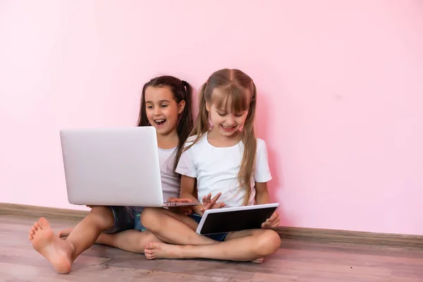 Niñas niños asombrados mostrando camiseta blanca, aislado sobre fondo rosa. Concepto de estilo de vida infantil. Prepara espacio para copias. Señalar el dedo índice a un lado —  Fotos de Stock