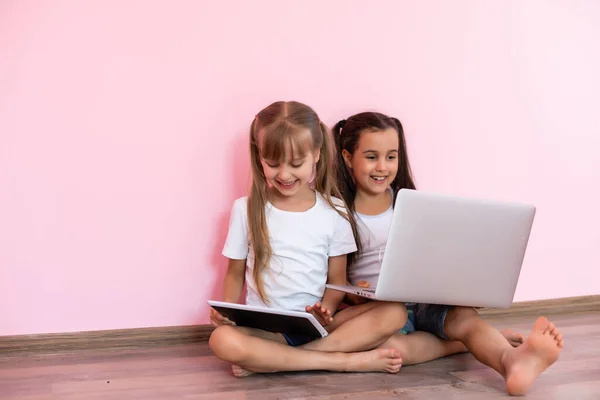 Dos niñas sentadas frente a un portátil y riendo, de cerca, emociones positivas, entretenimiento en Internet para niños —  Fotos de Stock