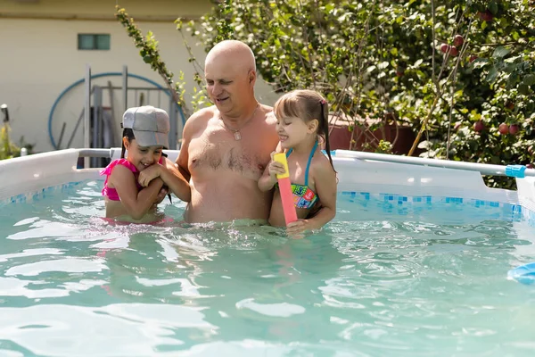 Portrait of a happy grandfather with grandchildren in pool