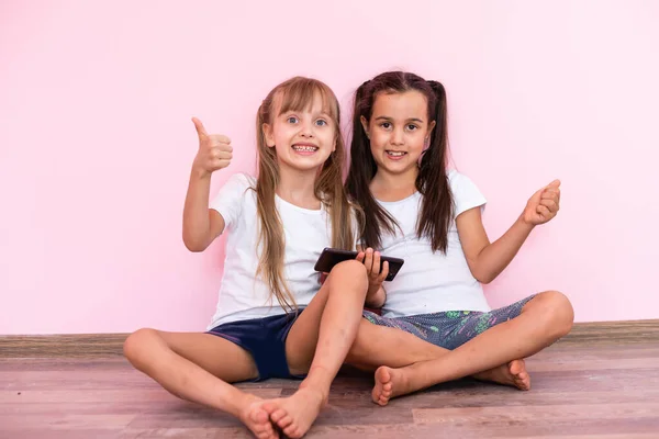 Twee kleine meisjes - beste vrienden, geïsoleerd over op een roze achtergrond — Stockfoto