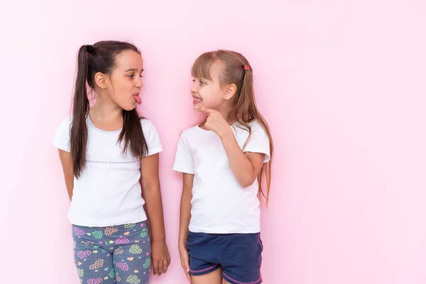 Twee meisjes vechten om een roze achtergrond — Stockfoto