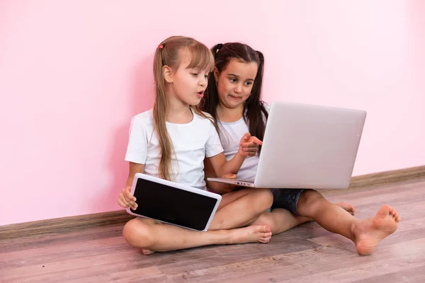 Due bambine sedute davanti a un computer portatile e ridendo, primo piano, emozioni positive, intrattenimento su Internet per bambini — Foto Stock