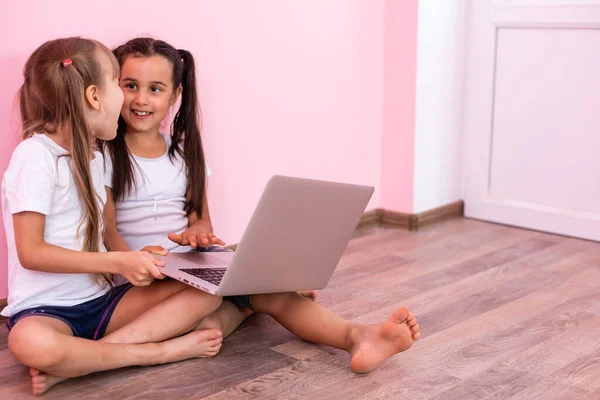 Dwie małe dziewczynki siedzące przed laptopem i śmiejące się, zbliżenie, pozytywne emocje, rozrywka w Internecie dla dzieci — Zdjęcie stockowe