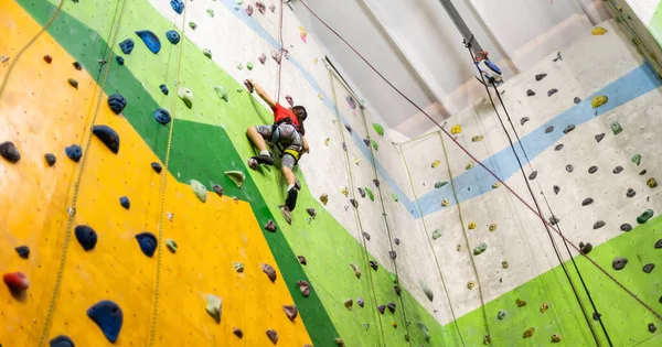 Sportliches kleines Mädchen klettert in Sporthalle auf künstlichen Boulder an praktischer Wand — Stockfoto