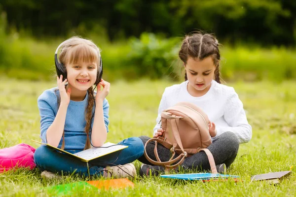 Zwei hübsche Schulmädchen sitzen mit Büchern draußen im Park. Schülerinnen oder Schüler erhalten Unterricht in der Natur. — Stockfoto