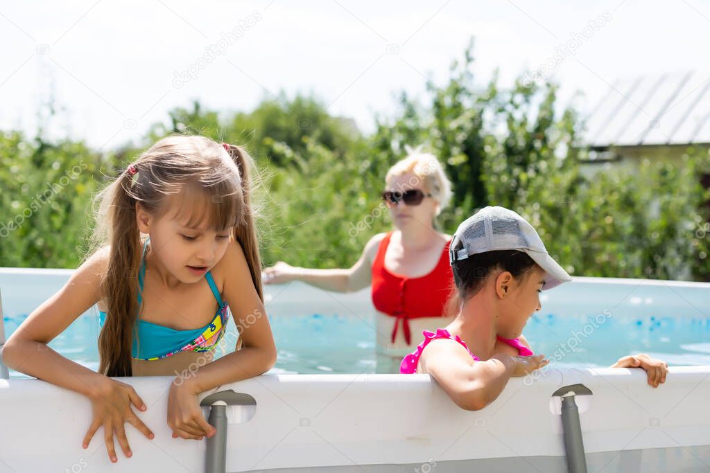 Mother and two daughters playing in pool water.Woman and two girls have fun in home pool splashing water and smiling