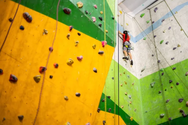 Sportig liten flicka klättring konstgjord sten på praktisk vägg i gym — Stockfoto