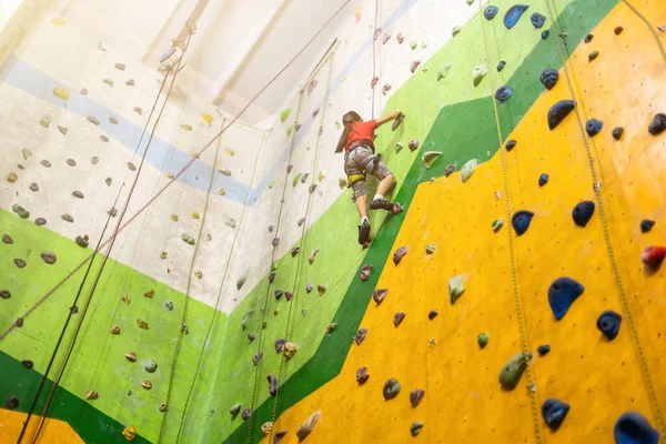Sportliches kleines Mädchen klettert in Sporthalle auf künstlichen Boulder an praktischer Wand — Stockfoto