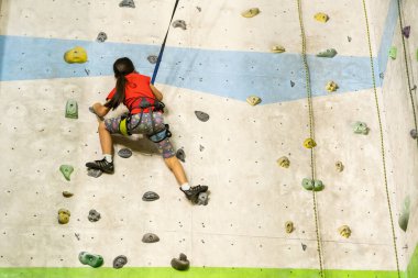 Küçük kız kaya duvarına tırmanıyor.