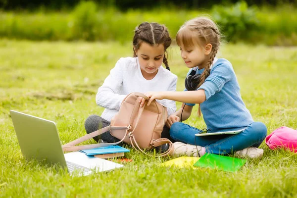 Dvě krásné sestry si během karantény dělají domácí úkoly. Děti používají gadgets pro učení. Vzdělávání, distanční vzdělávání, domácí výuka během karantény — Stock fotografie