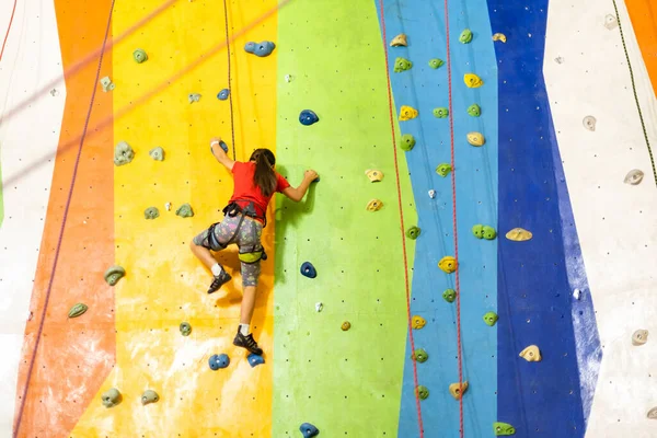 Sportig liten flicka klättring konstgjord sten på praktisk vägg i gym — Stockfoto
