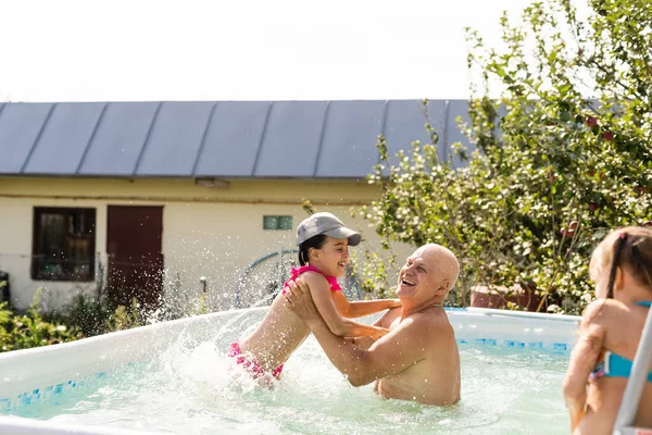 Portrait d'un grand-père heureux avec des petits-enfants dans la piscine — Photo