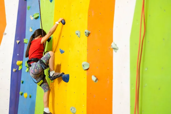 Liten flicka klättring Rock Wall praktisk vägg i gymmet — Stockfoto