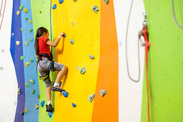 Liten flicka klättring Rock Wall praktisk vägg i gymmet — Stockfoto