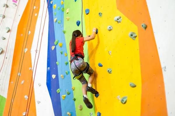 Liten flicka klättring Rock Wall praktisk vägg i gymmet — Stockfoto