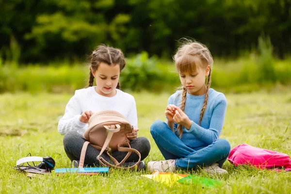 Дві красиві школярки сидять з книгами на відкритому повітрі в парку. Школярки або студенти викладають уроки на природі . — стокове фото