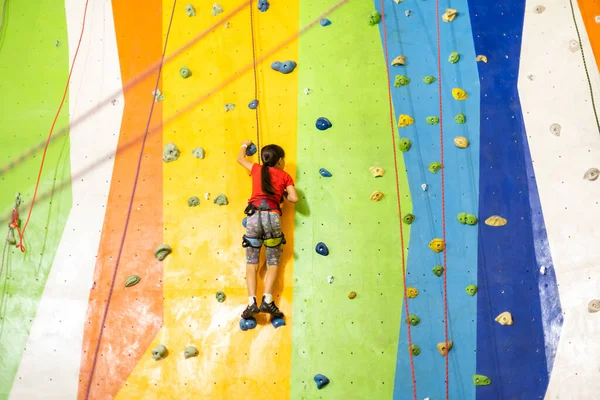 Liten flicka klättring Rock Wall praktisk vägg i gymmet — Stockfoto