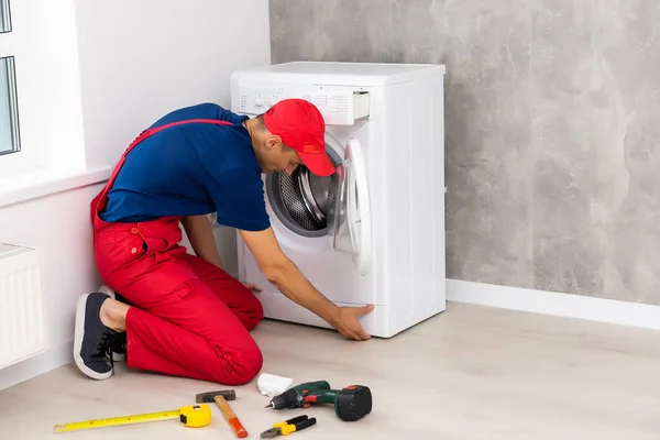 Klempner in Overalls mit Werkzeug repariert Waschmaschine im Haus — Stockfoto