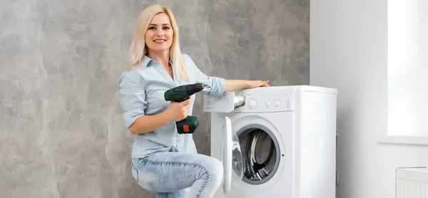 Mulher fixação quebrado máquina de lavar roupa — Fotografia de Stock