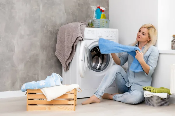 Egy fiatal háziasszony mosógéppel és ruhákkal. Mosás napja. — Stock Fotó