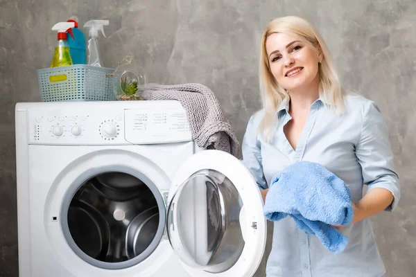 Uma jovem dona de casa com máquina de lavar roupa e roupas. Dia de lavagem. — Fotografia de Stock