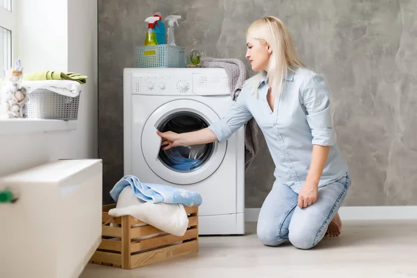 Una joven ama de casa con lavadora y ropa. Día de lavado. — Foto de Stock