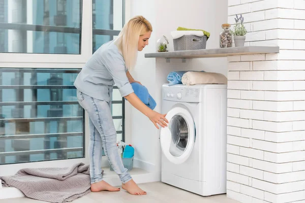 Una joven ama de casa con lavadora y ropa. Día de lavado. — Foto de Stock
