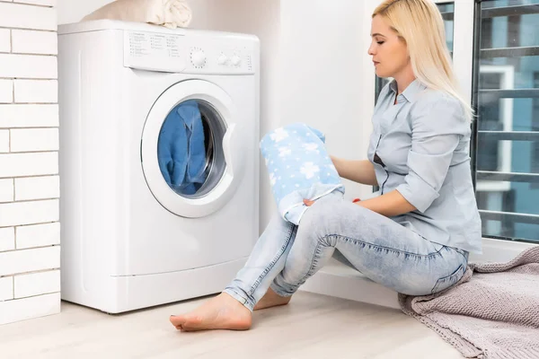 Una joven ama de casa con lavadora y ropa. Día de lavado. — Foto de Stock