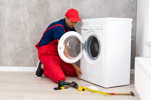 Mestre repara a máquina de lavar quebrada — Fotografia de Stock
