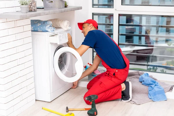 Masculino adulto reparador com ferramenta e prancheta verificando máquina de lavar roupa no banheiro — Fotografia de Stock