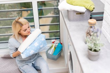 Çamaşır makinesi ve kıyafetleri olan genç bir ev hanımı. Yıkama Günü.