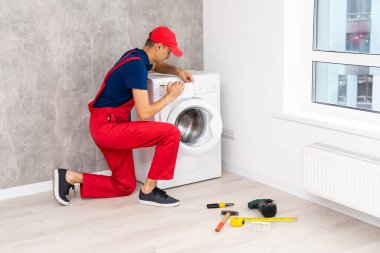 Usta bozuk çamaşır makinesini tamir ediyor.