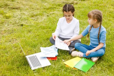 Pretty stylish schoolgirls studying online lesson in the courtyard, social distance during quarantine, self-isolation, online education concept clipart