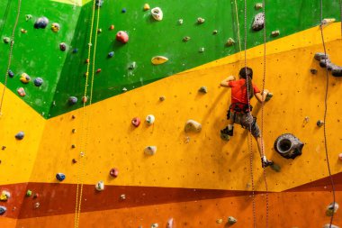 Küçük kız kaya duvarına tırmanıyor.