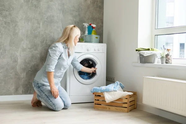 Μια νεαρή νοικοκυρά με πλυντήριο και ρούχα. Ημέρα πλύσης. — Φωτογραφία Αρχείου