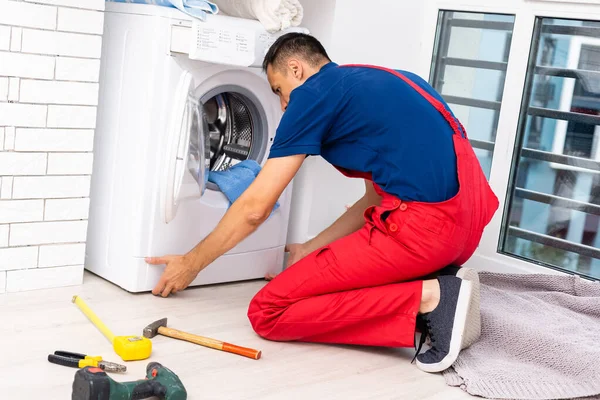 Usta bozuk çamaşır makinesini tamir ediyor. — Stok fotoğraf