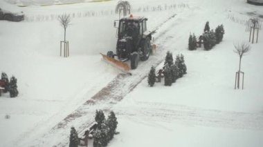 Traktör kazıcı şehir bahçesindeki karı kaldırıyor. kamu hizmetlerinin çalışması