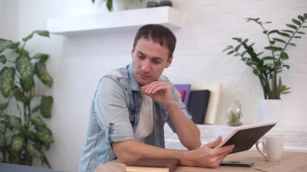 Продуманий серйозний молодий чоловік студент письменник сидить на домашньому офісному столі з ноутбуком, думаючи про натхнення пошук проблемних рішень ідеї втрачені в думках концепція мріяти озираючись — стокове відео