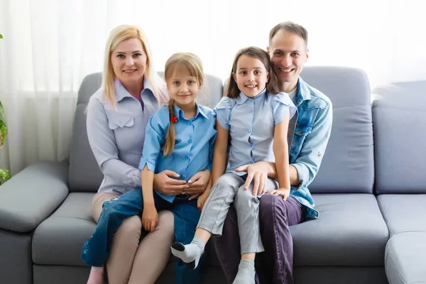 Wesoła młoda rodzina z dziećmi śmiejącymi się siedzącymi razem na kanapie, rodzice z dziećmi bawiącymi się w domu — Zdjęcie stockowe