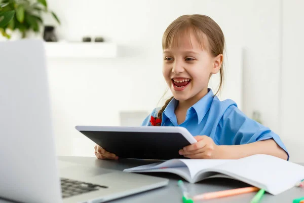 Απομακρυσμένα μαθήματα. Το παιδί χαμογελά χαρούμενο και αποκτά γνώση εξ αποστάσεως. Κοριτσάκι μελέτη online μάθηση από το σπίτι. Online σχολείο. — Φωτογραφία Αρχείου