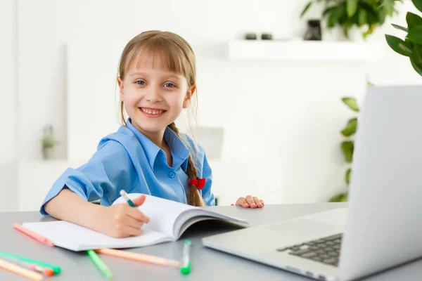 Lecciones remotas. El niño sonríe felizmente y obtiene conocimiento remotamente. Niña estudia en línea aprendiendo desde casa. Escuela en línea. —  Fotos de Stock