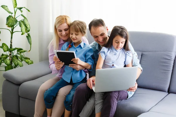 Familia feliz de cuatro padres y niños pequeños lindos disfrutan usando la tableta, viendo dibujos animados, hacer videollamadas por Internet o ir de compras en línea mirando la pantalla de la computadora sentarse juntos en casa — Foto de Stock