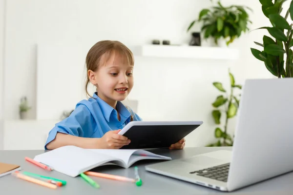 Lecciones remotas. El niño sonríe felizmente y obtiene conocimiento remotamente. Niña estudia en línea aprendiendo desde casa. Escuela en línea. —  Fotos de Stock