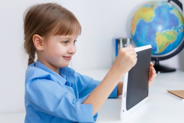 Sınıfta dijital tableti olan zeki bir kız. İlkokulda bir çocuk. Çocuklar için eğitim ve öğrenim.